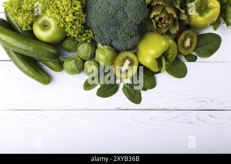 Mischung aus grünem Obst und Gemüse, Kiwi, Gurke, Brokkoli, grünem Apfel, Artischocken, rosenkohl, Spinat, Kopfsalat auf weißem hölzernem Hintergrund. Sa Stockfoto