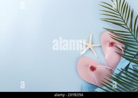 Sommerferien, pinkfarbene Badeschuhe, Handtuch, Palmenzweig und Muscheln auf blauem Hintergrund Stockfoto