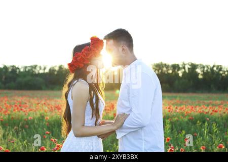 Junges Paar in Liebe küssen und umarmen im Mohnfeld Stockfoto