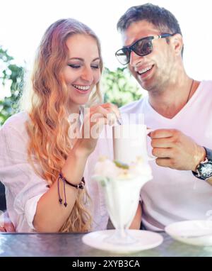 Junges Paar genießen Kaffee in einem Straßencafé Lachen und teilen ein Eis Stockfoto