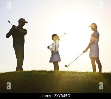 Familie von einem Golfer Golfspielen im Sonnenuntergang Stockfoto