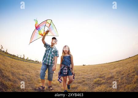 Glückliche kleine Kinder spielen mit Drachen auf der Sommerwiese Stockfoto