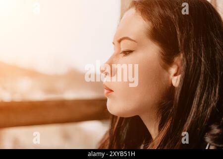 Eine junge Frau, die an einem sonnigen Tag aus dem Fenster schaut Stockfoto