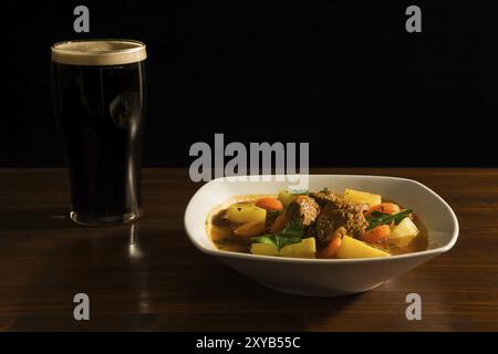 Traditioneller irischer Eintopf mit einem Pint Bier auf einem Tisch Stockfoto