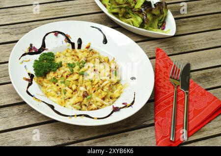 Käsespätzle auf einem Teller mit Salat. Käsespätzle auf einem Teller mit Salat Stockfoto