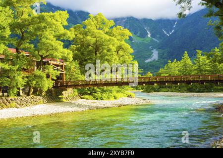 Man überquert die Kappa-Bashi-Brücke mit dem Hintergrund des Mount Hotaka am frühen sonnigen Morgen in den Japanischen Alpen in Kamikochi, Präfektur Nagano, Japan. H Stockfoto