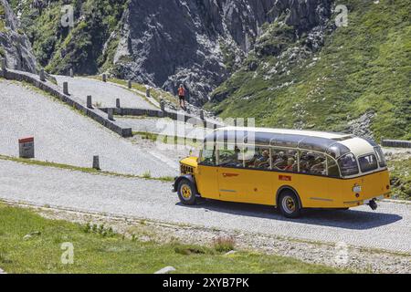 Der historische postbus fährt entlang der Tremola, der weltberühmten Serpentinenstraße durch das Val Tremolo. Touristenbus auf der Tremola-Straße, Schweiz Stockfoto