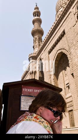 Ein Tourist spricht auf ihrem Handy vor dem Tor der Madrassa von Sultan Hassan & Al Rifa'i Moschee in der Nähe der Zitadelle in Kairo, Ägypten. Stockfoto