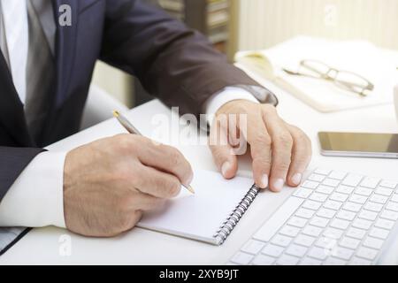 Männliche Hände mit modernen Computer und Schreiben in einem notepad Geschäftskonzept Nahaufnahme Stockfoto