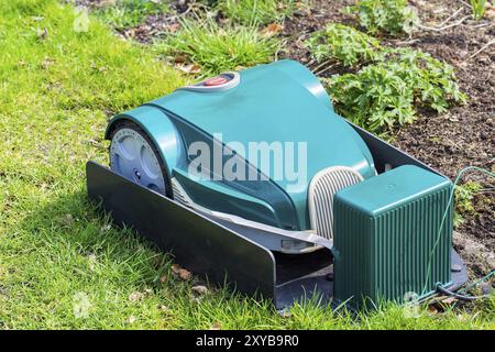 Grüne elektrische Mähroboter laden auf Gras Stockfoto