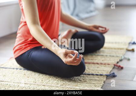 Attraktive junge brünette Frau trainieren und Sitzen in Yoga lotus Position während zu Hause ausruhen Stockfoto