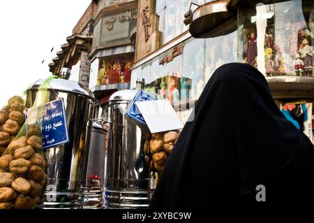 Eine ägyptische Frau, die bei einem Tamarindensaftverkäufer auf dem Khal El Khalili-Markt in Kairo steht. Stockfoto