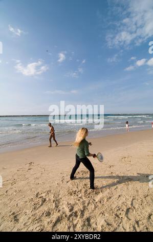 Eine israelische Frau, die an einem sonnigen Wintertag in Tel Aviv, Israel, Strandtennis spielt. Stockfoto