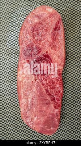 Ein Stück Lendenfleisch wird in Scheiben geschnitten und auf ein Backblech gelegt. Das Fleisch ist rosa und hat eine Menge Textur Stockfoto