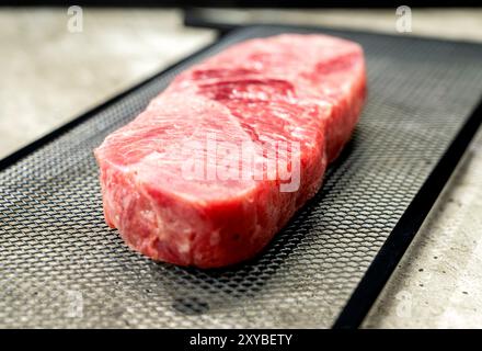 Ein Stück Lendenfleisch wird in Scheiben geschnitten und auf ein Backblech gelegt. Das Fleisch ist rosa und hat eine Menge Textur Stockfoto