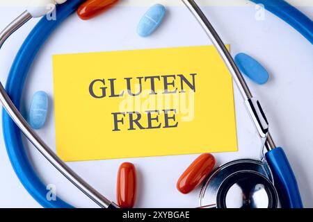 GLUTENFREIE Wörter auf einer gelben Visitenkarte in einer Komposition mit Stethoskop und Pillen Stockfoto