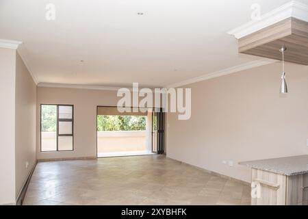 Blick auf das Wohnzimmer eines neu gebauten und leerstehenden Hauses mit Blick von der Küche, durch den Wohnbereich, zur Terrasse Stockfoto