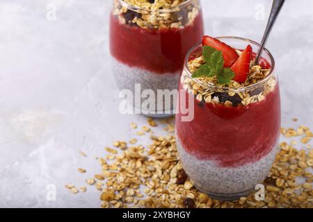 Gesunder Chia, Kokos, Erdbeerpudding mit hausgemachtem Müsli auf weißem Holztisch Stockfoto