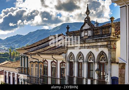 Fassade der alten Häuser in der kolonialen Architektur mit ihren Balkonen, Dächer und farbenfrohen Details mit den Bergen im Hintergrund in der histo Stockfoto