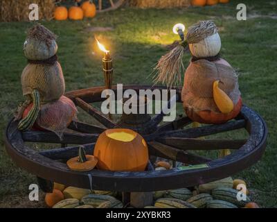 Zwei Kürbisskulpturen sitzen auf einem Holzrad, begleitet von einer geschnitzten Kürbislaterne und Fackel, borken, münsterland, Deutschland, Europa Stockfoto
