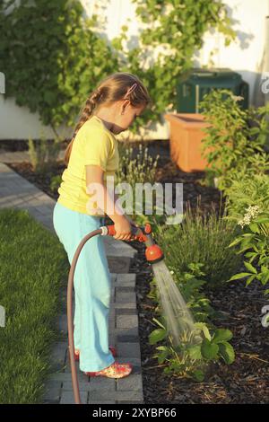 Kleines Mädchen, den Rasen im Garten Bewässerung Stockfoto