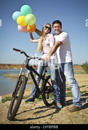 Glückliches lächelndes Paar mit Ballons auf dem Fahrrad Stockfoto