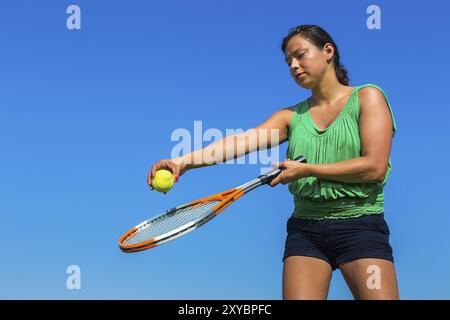 Junge kolumbianische Frau mit Tennisschläger und Ball gegen den blauen Himmel Stockfoto