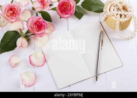 Öffnen Sie leeres Tagebuch oder Tagebuch mit Kugelschreiber, rosa Rosen und Perlen auf Holztisch, romantisches Konzept mit Blick über dem Kopf Stockfoto