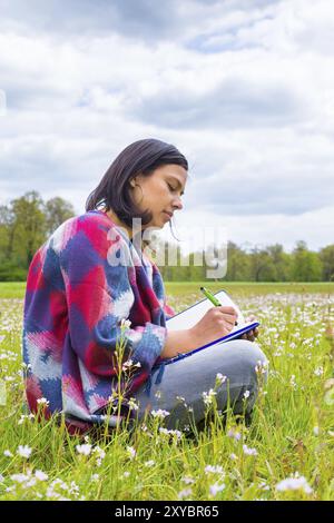 Kolumbianische Frau schreiben in blühende Weide mit Frühling Blumen Stockfoto