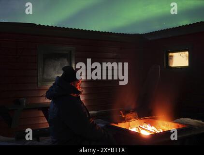 Aufwärmen in einer sehr kalten Nacht mit Nordlichtern in Lappland Stockfoto