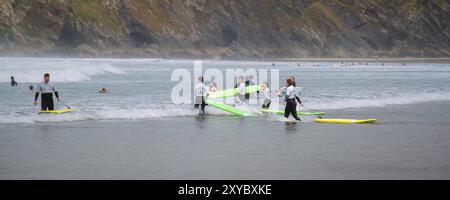 Ein Panoramablick von Urlaubern, die eine Surfstunde am GT Great Western Beach in Newquay in Cornwall in Großbritannien genießen. Stockfoto