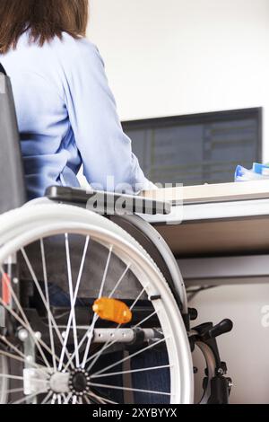 Ungültige oder behinderte junge geschäftsfrau sitzende Person Rollstuhl arbeiten Büro Schreibtisch computer Stockfoto