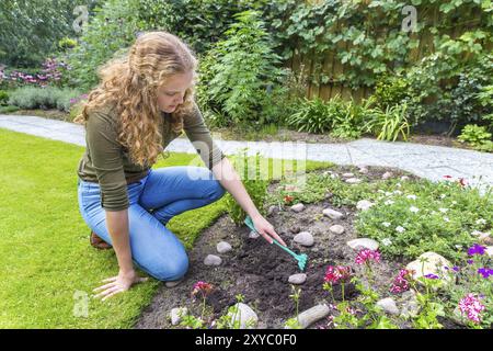 Niederländische Teenager-Mädchen mit Rechen draußen im Garten arbeiten Stockfoto