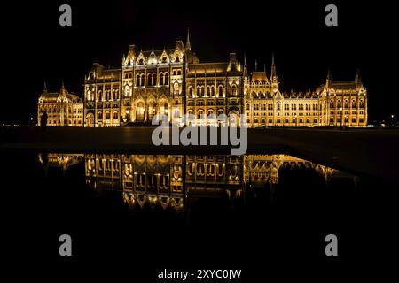 Ungarn, Budapest, ungarisches Parlamentsgebäude, beleuchtet bei Nacht mit Spiegelspiegelung im Wasser, Europa Stockfoto