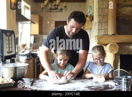 Vater und seine zwei kleinen Helfer. Kinder kochen hausgemachtes Brot mit es Vater Stockfoto