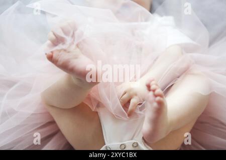 Adorable lustig Baby Mädchen tragen tu-tu Rock auf dem Bett. In der Nähe der Füße des Babys Stockfoto