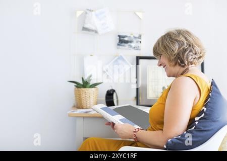 Reife Frau lesen Buch im Wohnzimmer Stockfoto