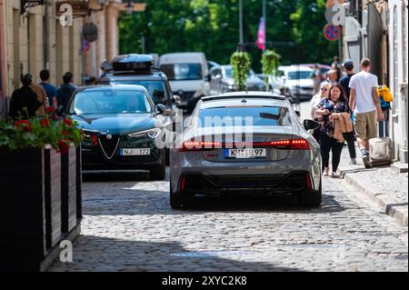 Riga, Lettland, 29. Mai 2023: Autos fahren an einem sonnigen Tag auf einer kopfsteingepflasterten Straße in einem pulsierenden Stadtgebiet Stockfoto