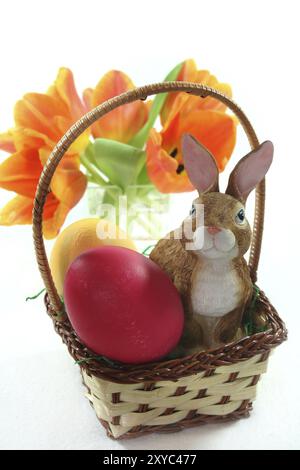 Osterkorb mit Ostereiern und Osterhase und Tulpen vor weißem Hintergrund Stockfoto