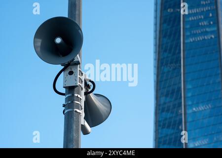 Straßenlautsprecher an einem Pol vor dem Hintergrund einer Glasfassade eines modernen Gebäudes Stockfoto