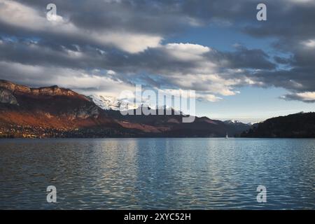 Schneebedeckte Berge neben dem wunderschönen französischen See, dem See Annecy, in den Alpen an einem teilweise bewölkten Tag Stockfoto