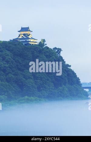 Eine schöne Schicht Nebel deckt der Kiso-Fluss unterhalb einer beleuchteten Burg Inuyama am Abend in der Präfektur Gifu, Japan. Vertikal Stockfoto