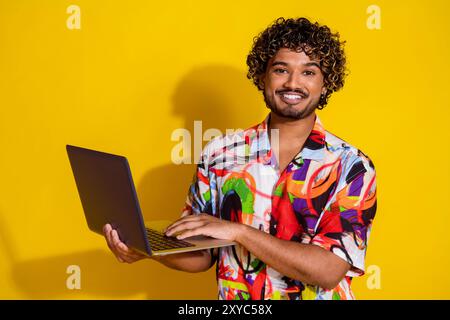 Foto des netten jungen Mannes Benutzung Laptop-Hemd isoliert auf gelbem Hintergrund Stockfoto