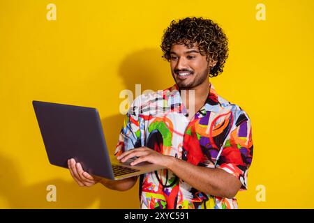 Foto des netten jungen Mannes Benutzung Laptop-Hemd isoliert auf gelbem Hintergrund Stockfoto