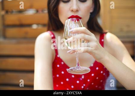 Close up Portrait von brünette Frau mit Polka Dots Kleid in Wein in einem Restaurant Stockfoto