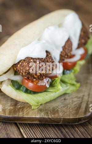 Frisch zubereitetes Falafel Sandwich (Nahaufnahme, selektiver Fokus) auf einem alten Holztisch Stockfoto