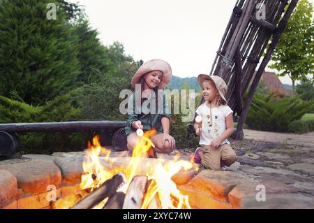 Zwei glückliche Schwestern Rösten Marshmallows am Lagerfeuer am Abend Stockfoto