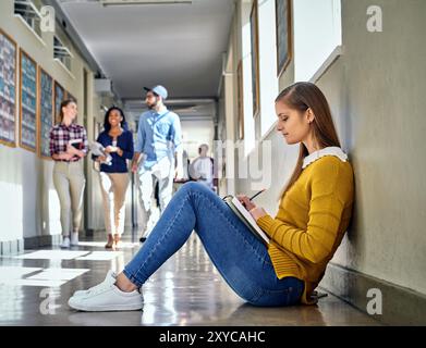 Universität, Mädchen und Studium auf dem Boden im Flur für Bildung, Lernen und Vorbereitung auf die Prüfung. Campus, Student und weibliche Person mit Einbuchung Stockfoto