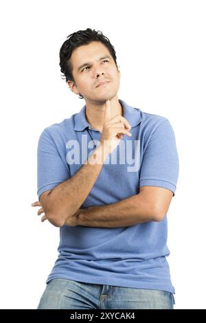 Ein gutaussehender hispanischer Mann in legeren Kleidern mit gekreuzten Armen, Finger unter dem Kinn, sich wunderend, konzentriert, sich einen Gedanken oder eine Erinnerung vorstellt, die nach einem sucht Stockfoto