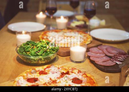 Tabelle mit verschiedenen Lebensmitteln mit Rotwein und Kerzen serviert. Stockfoto